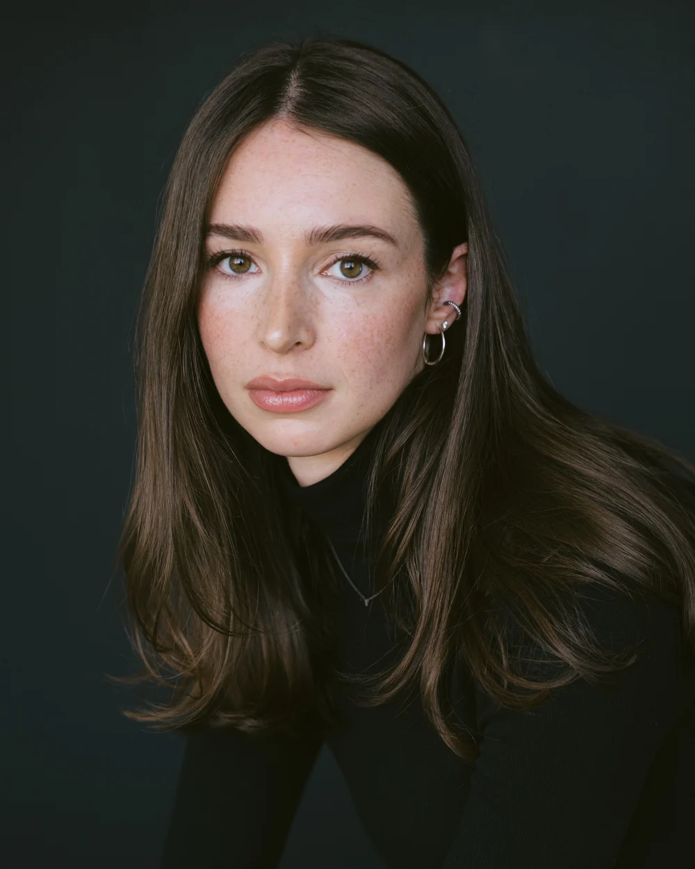 Portrait of Paige Latimer in a black turtleneck against a dark backdrop